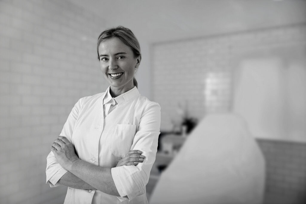cosmetologist with crossed arms standing in her cabinet